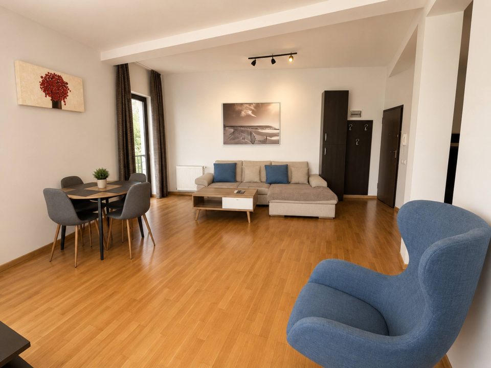 Livingul spre intrare: canapeaua extensibilă, masa rotundă și fotoliul albastru